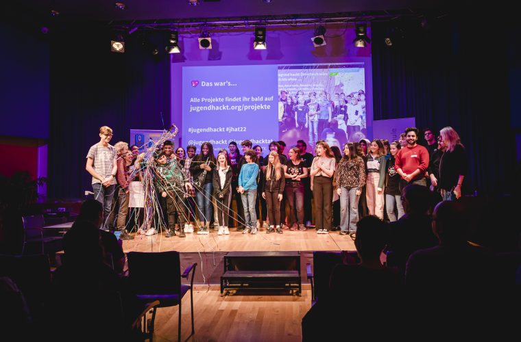 Teilnehmer_innen und Mentor_innen auf der Bühne der Abschlusspräsentation von Jugend hackt Österreich 2022