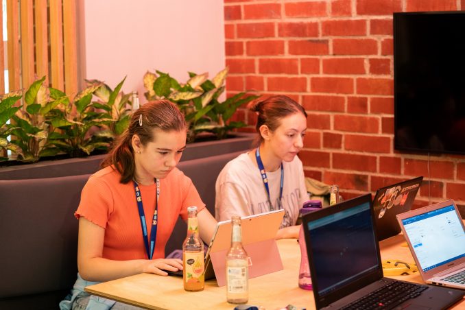 Zwei Jugendliche sitzen konzentriert an ihren Laptops bei der Projektarbeit.